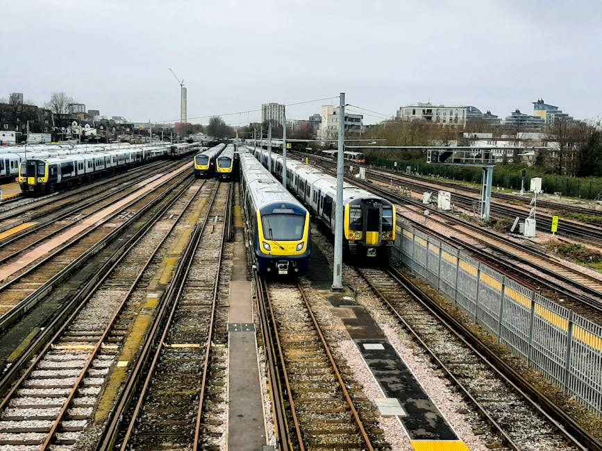 A railway station platform with a large, white directional sign displaying various transportation options, including an arrow pointing to the left for 'Way out' and national rail bus services, an arro
